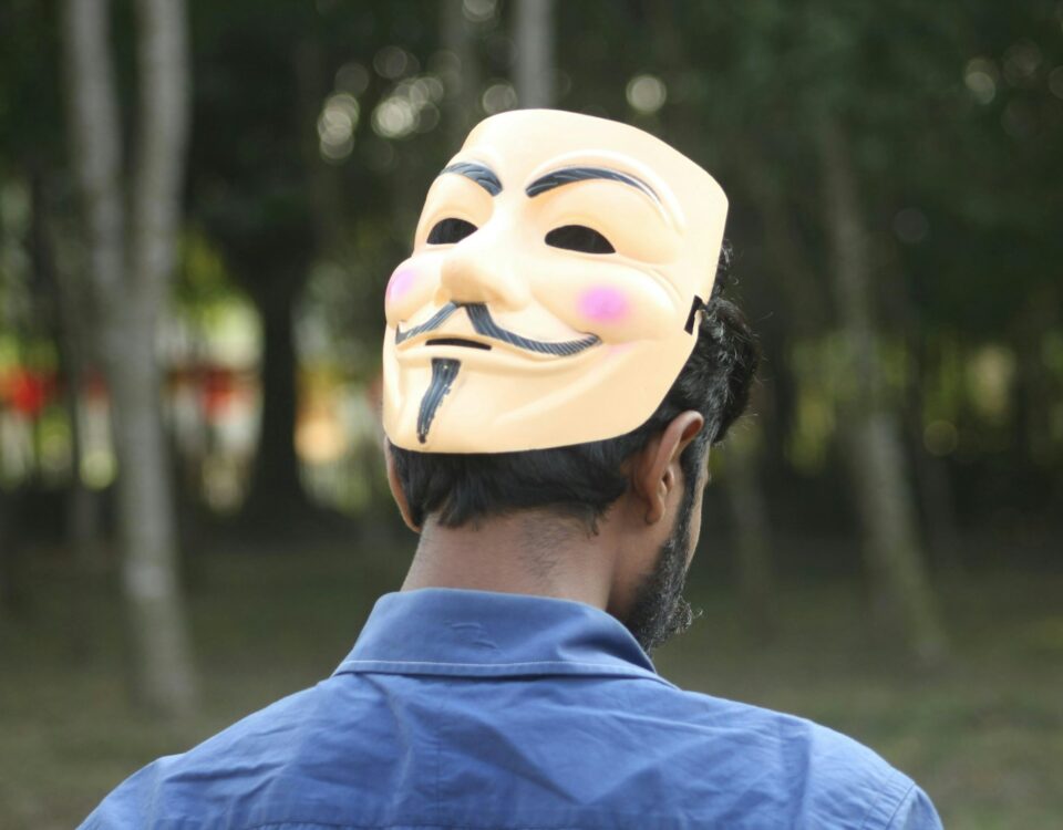 Man wearing an anonymous mask looking away.
