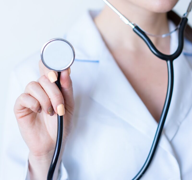 a woman in a white shirt holding a stethoscope